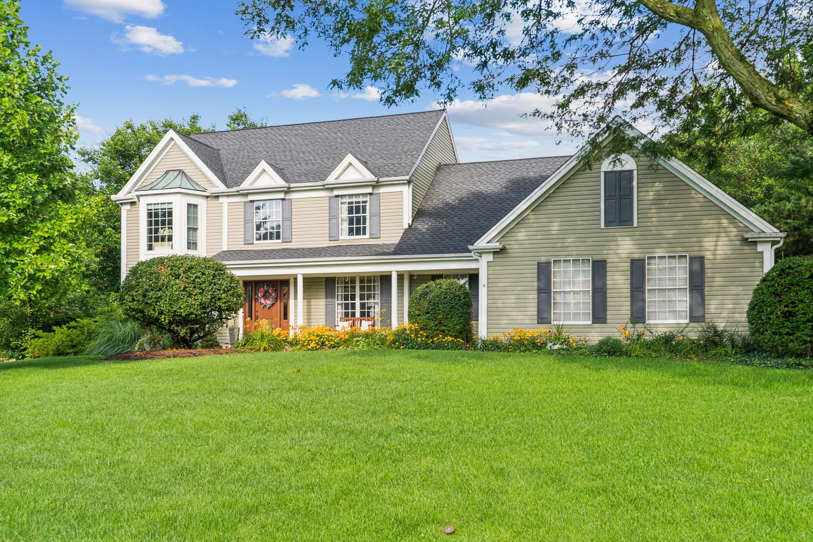 a view of a white house next to a yard with plants and trees