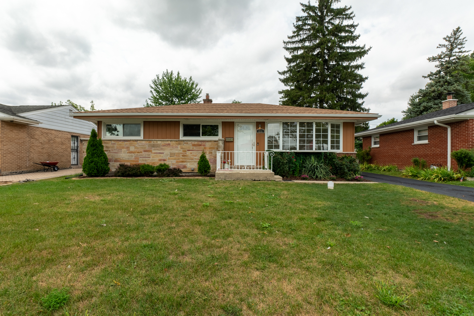 a front view of a house with a garden and trees