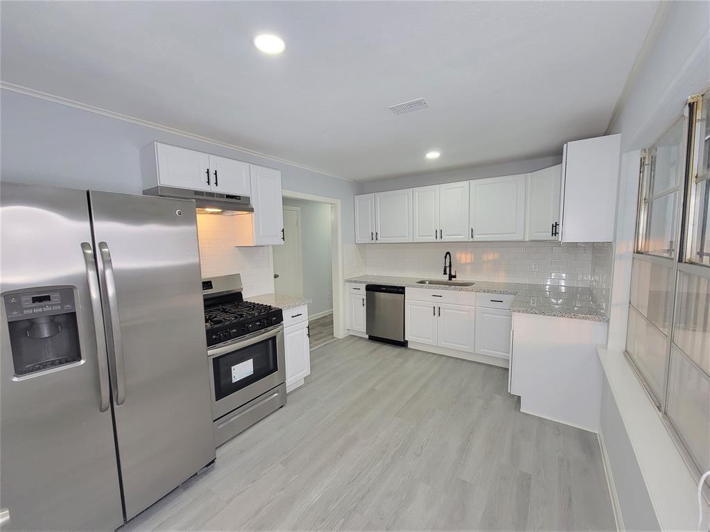 a kitchen with white cabinets and stainless steel appliances