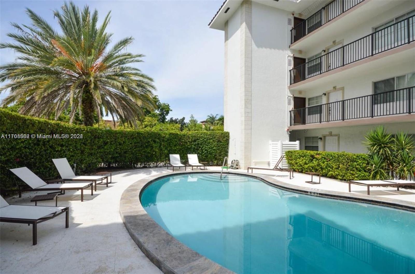 a view of a swimming pool with a lounge chair and palm trees