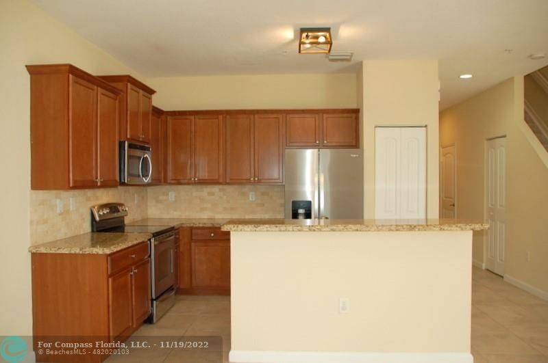 a kitchen with stainless steel appliances granite countertop a sink a stove and a refrigerator