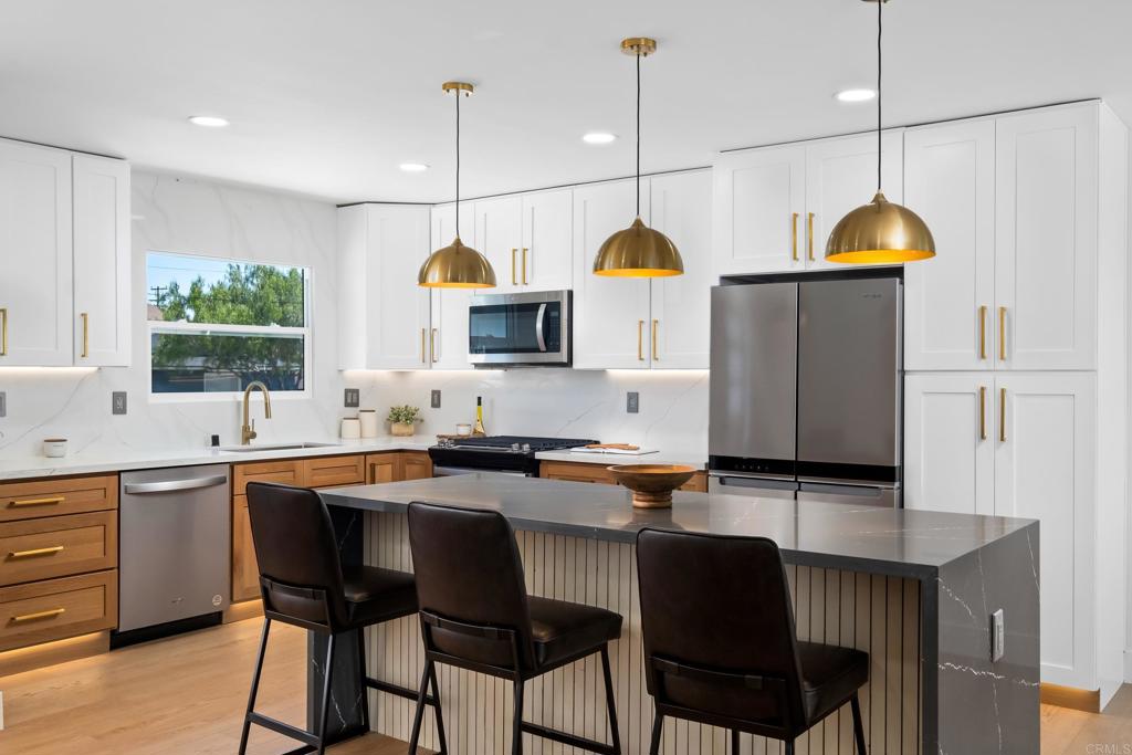 a kitchen with stainless steel appliances granite countertop a sink a stove and chairs