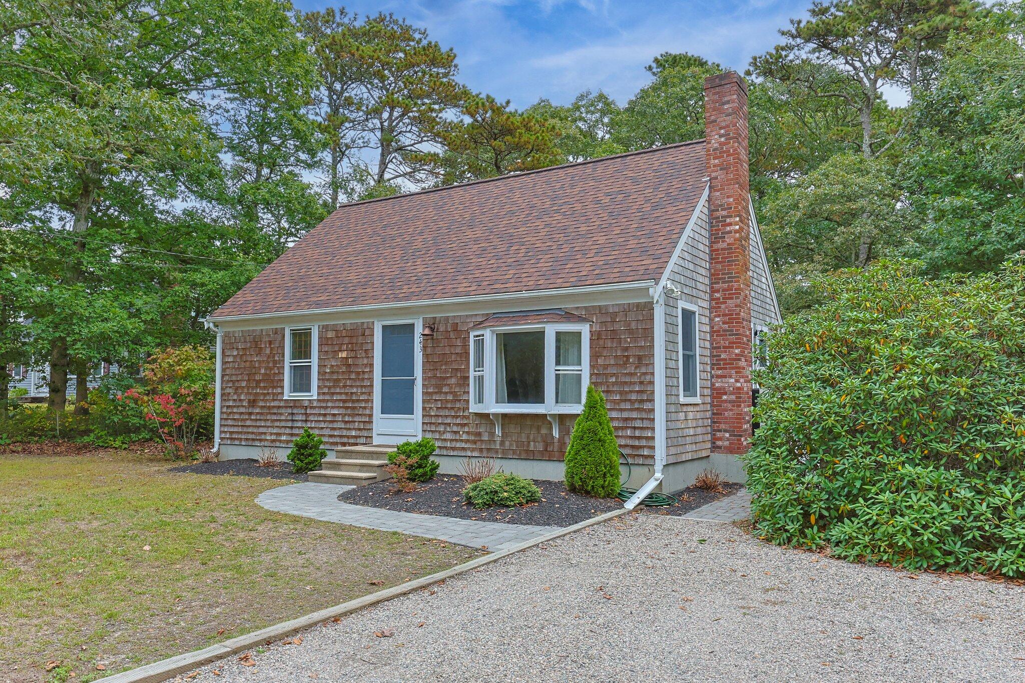 a front view of a house with a yard and trees