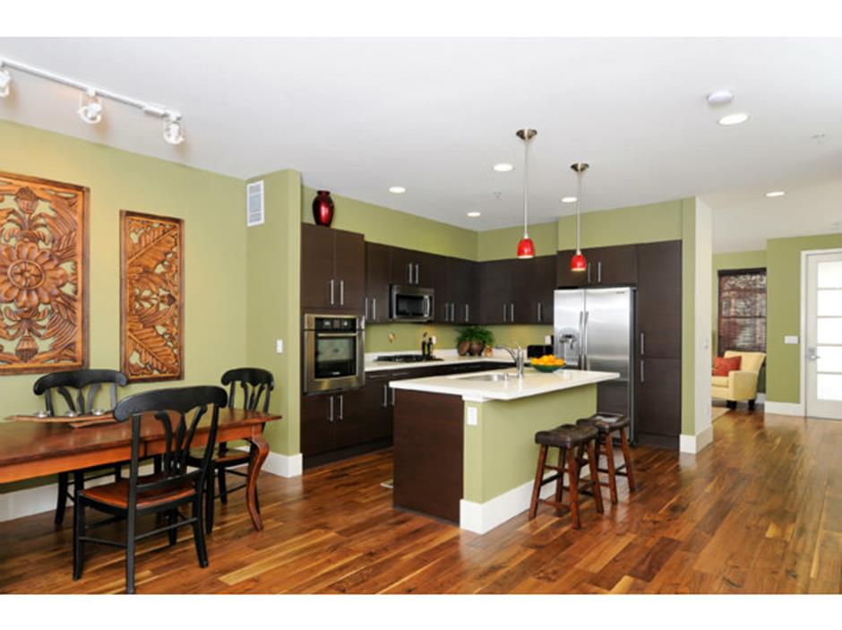 a kitchen with stainless steel appliances kitchen island granite countertop a table chairs sink and cabinets