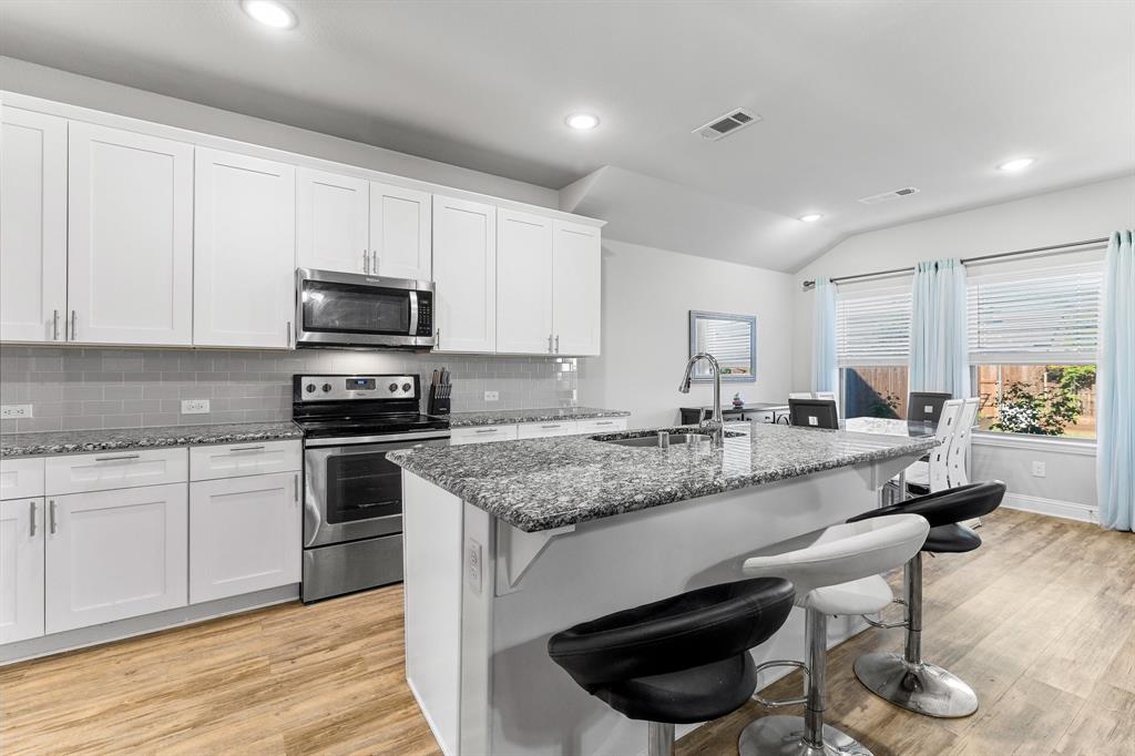 a kitchen with stainless steel appliances granite countertop a stove a sink and a microwave