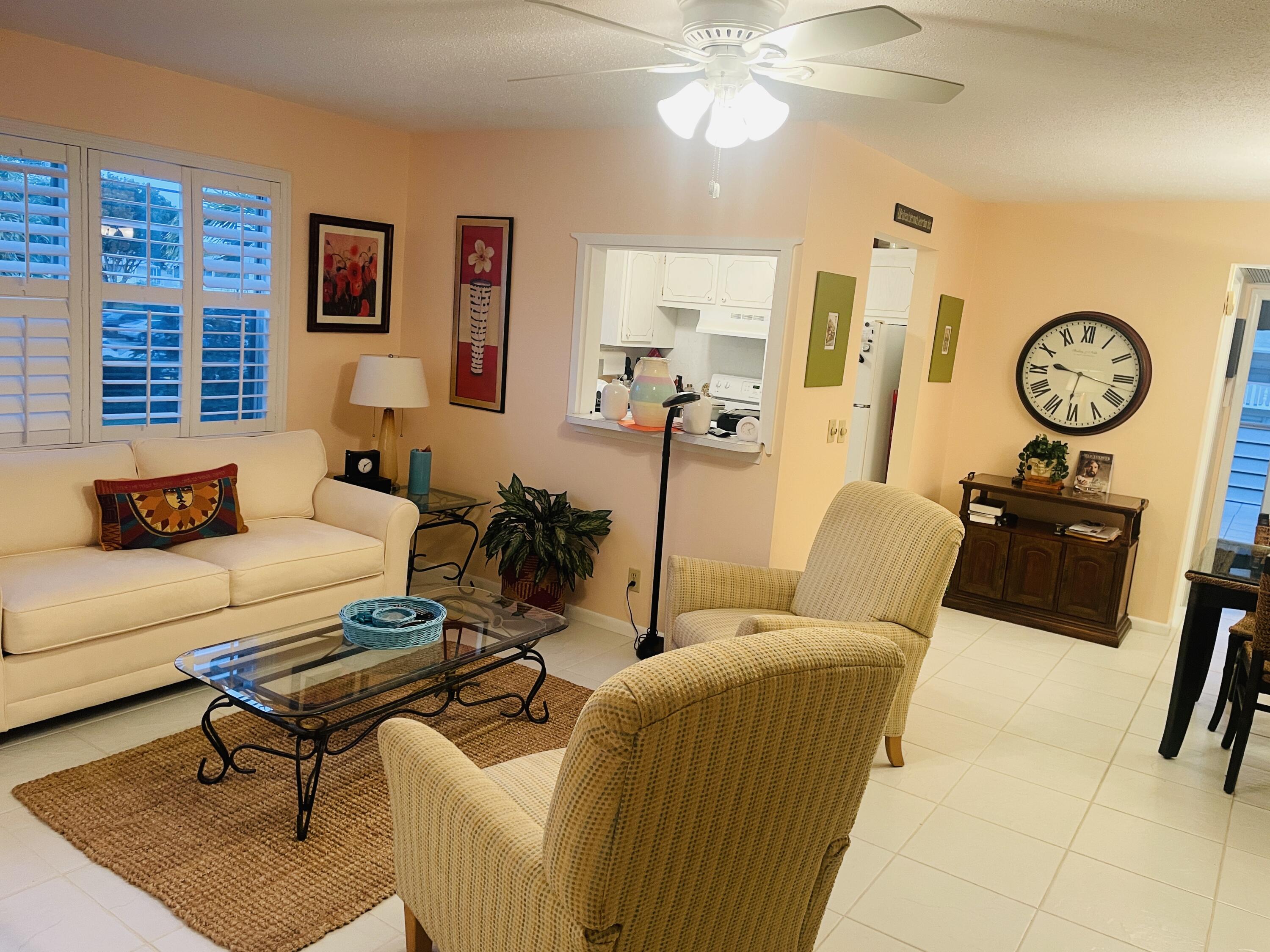 a living room with furniture a clock on wall and a window