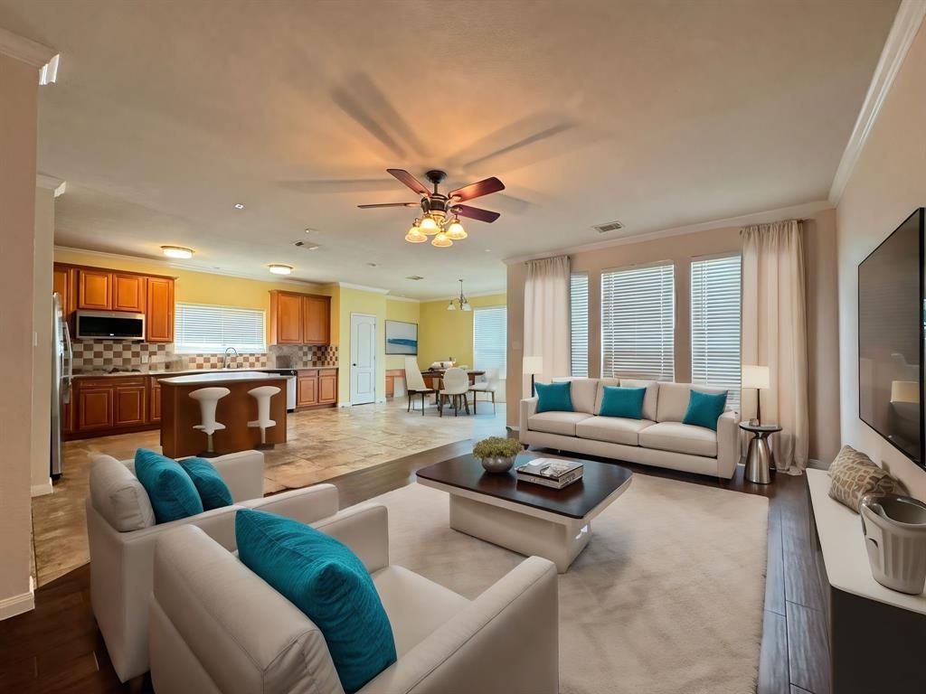 a living room with furniture ceiling fan and a flat screen tv