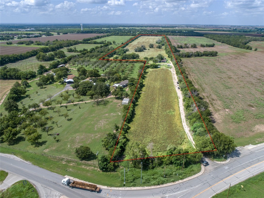 an aerial view of a residential houses with outdoor space and trees