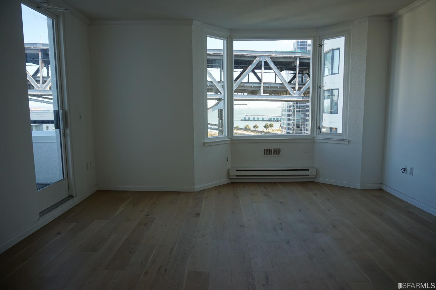 an empty room with wooden floor cabinet and windows