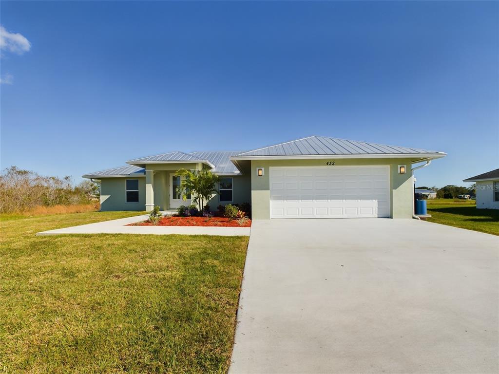 a front view of a house with a garden and lake view