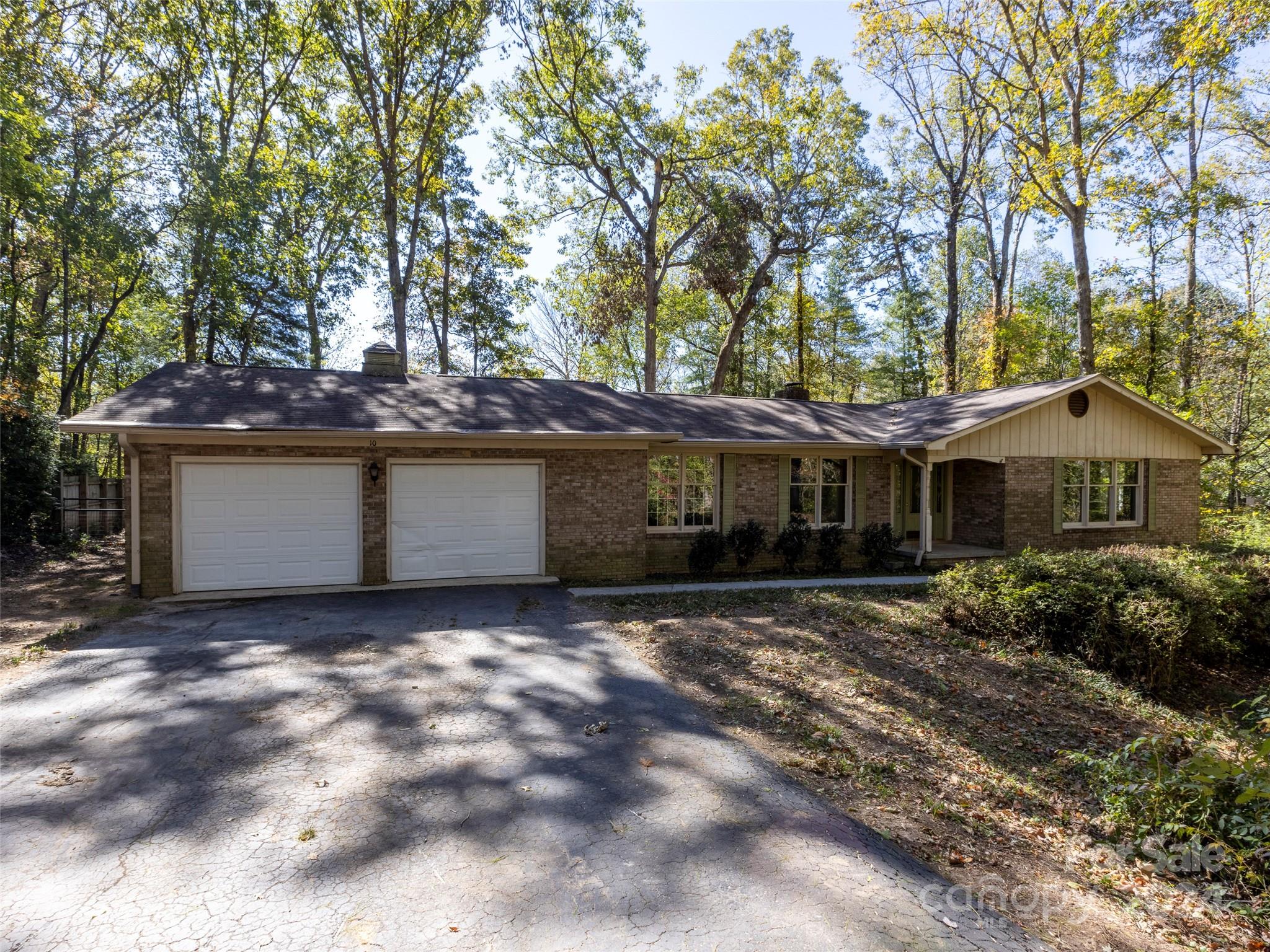 a view of house with outdoor seating and covered with trees