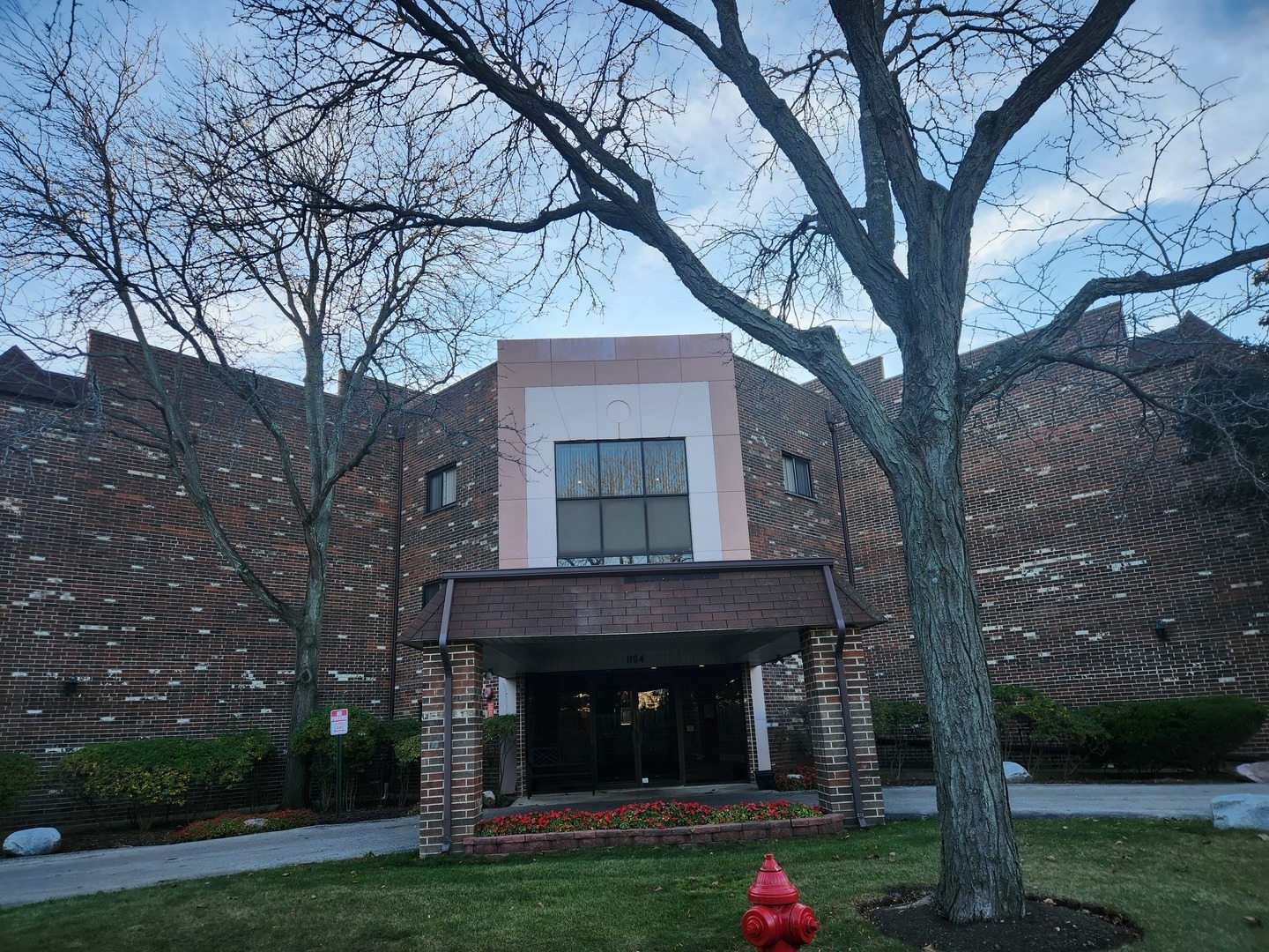 a view of a brick house with large windows and a large tree