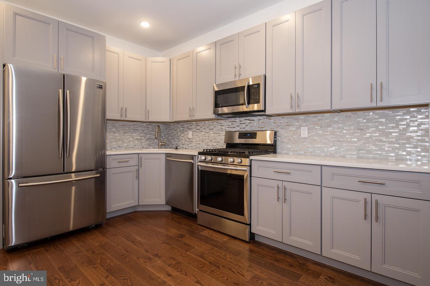 a kitchen with cabinets stainless steel appliances and wooden floor