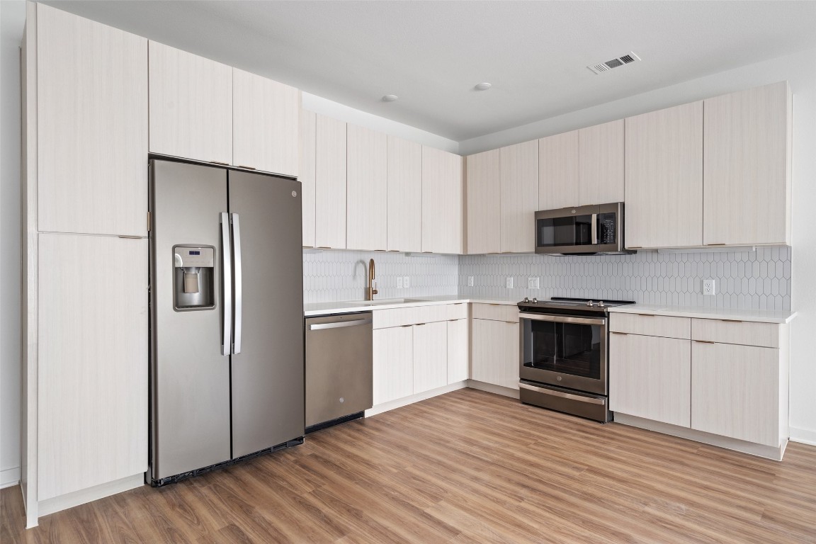 a kitchen with a refrigerator stove and white cabinets