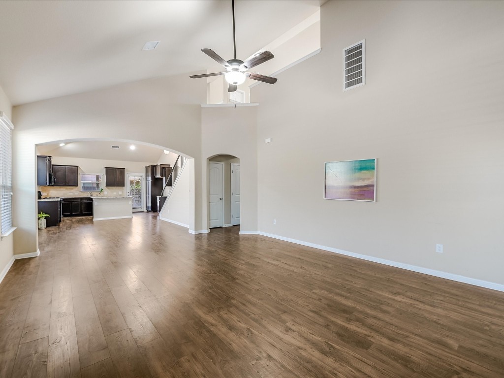 a view of a livingroom with furniture wooden floor a ceiling fan and windows