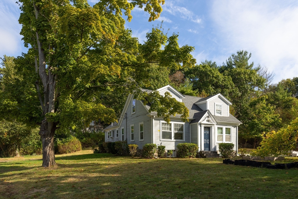 a front view of a house with a garden and tree