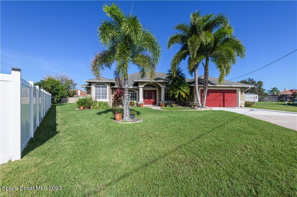 a view of a house with a yard and palm tree