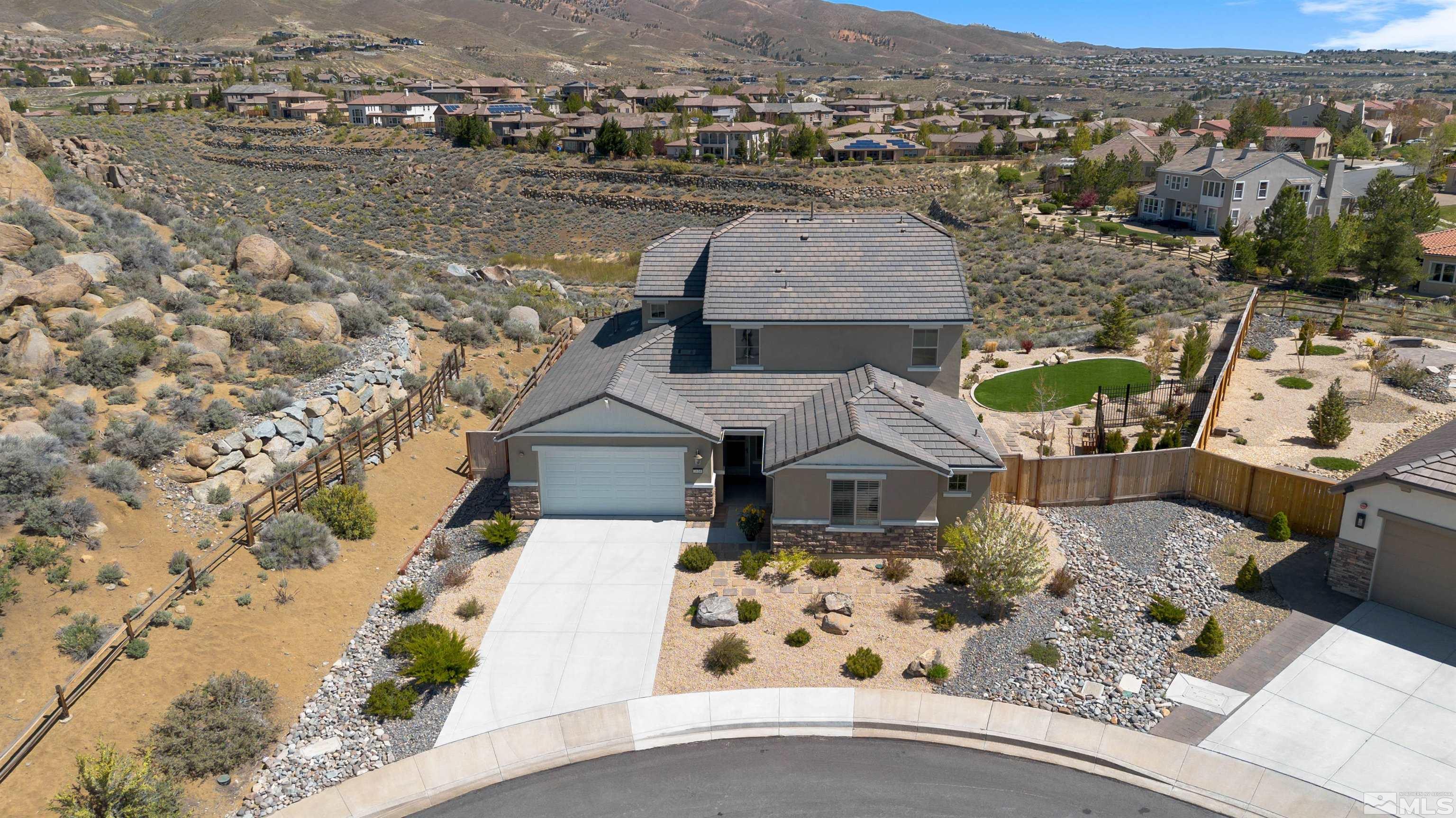 an aerial view of a house with a yard lawn chairs and large trees