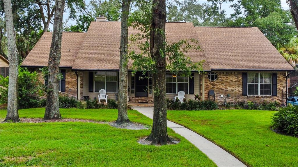 a front view of a house with a yard garden and a tree