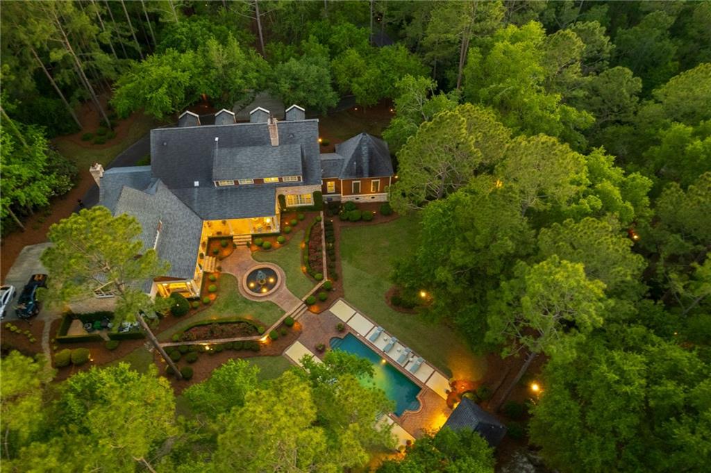 an aerial view of residential house with outdoor space and trees all around