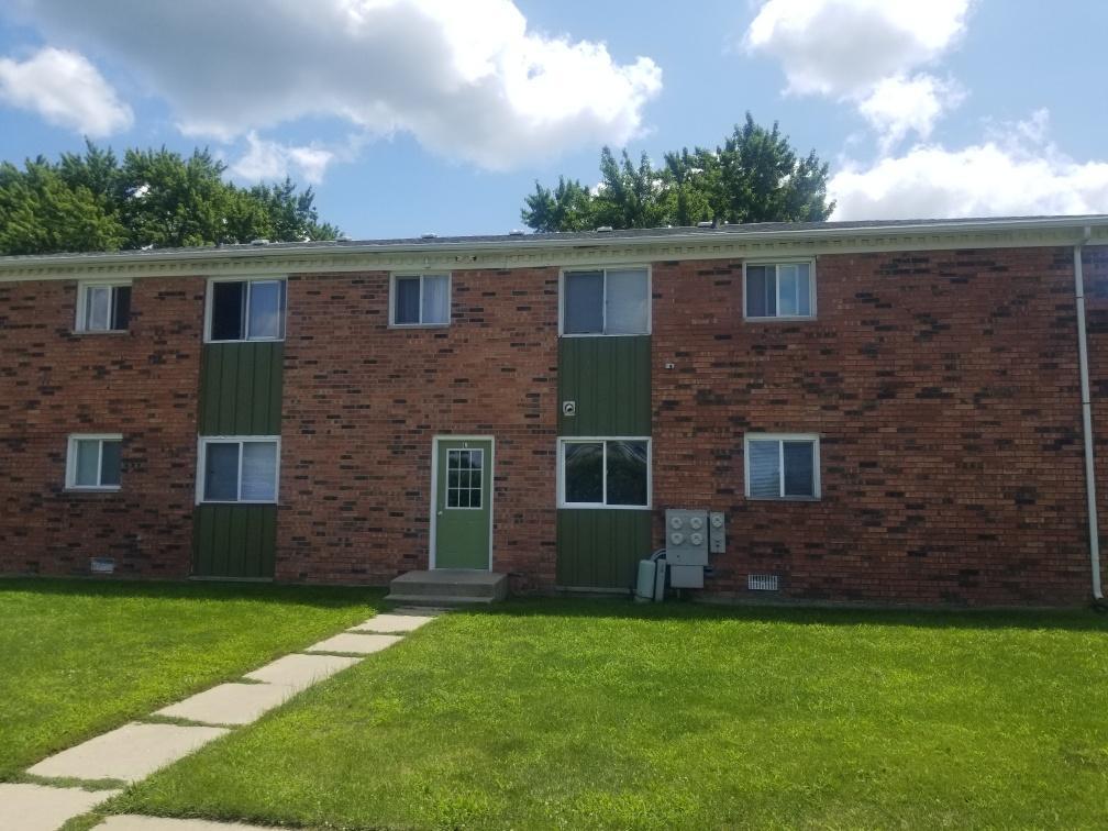 a brick house that has a small yard and large trees