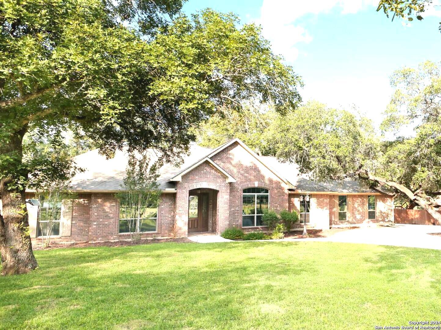 a front view of a house with a garden and trees