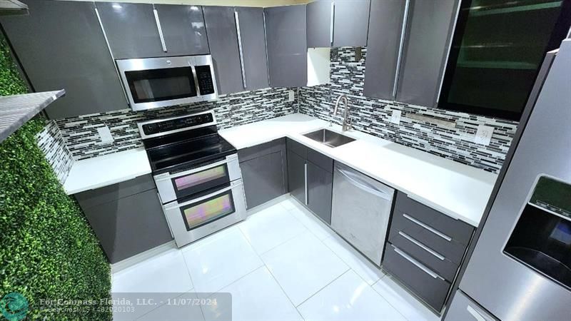 a kitchen with granite countertop a stove microwave and sink