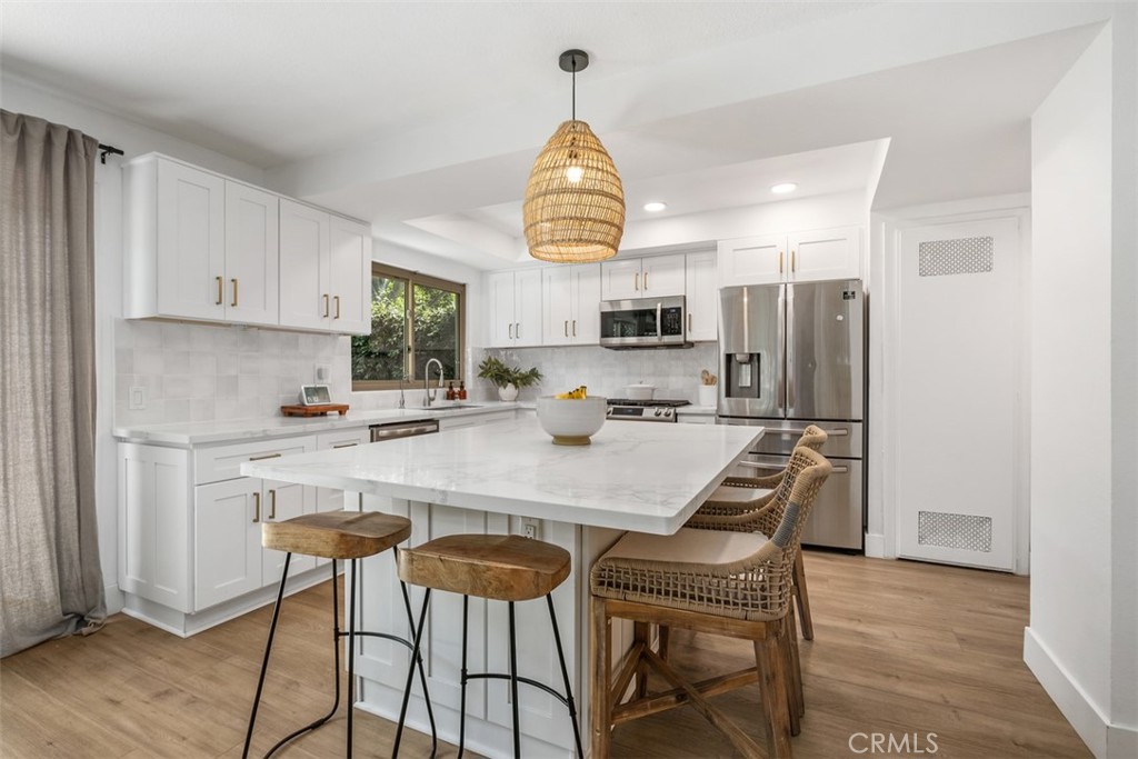 a kitchen with stainless steel appliances granite countertop a dining table chairs refrigerator and cabinets