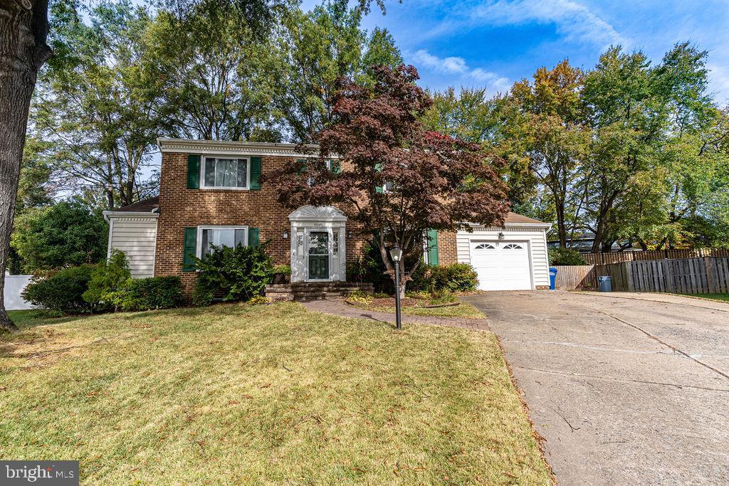 a front view of a house with a yard and tree