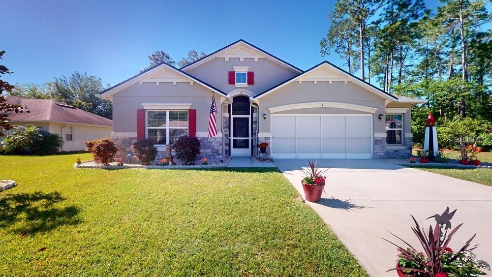 a front view of house with yard and trees in the background