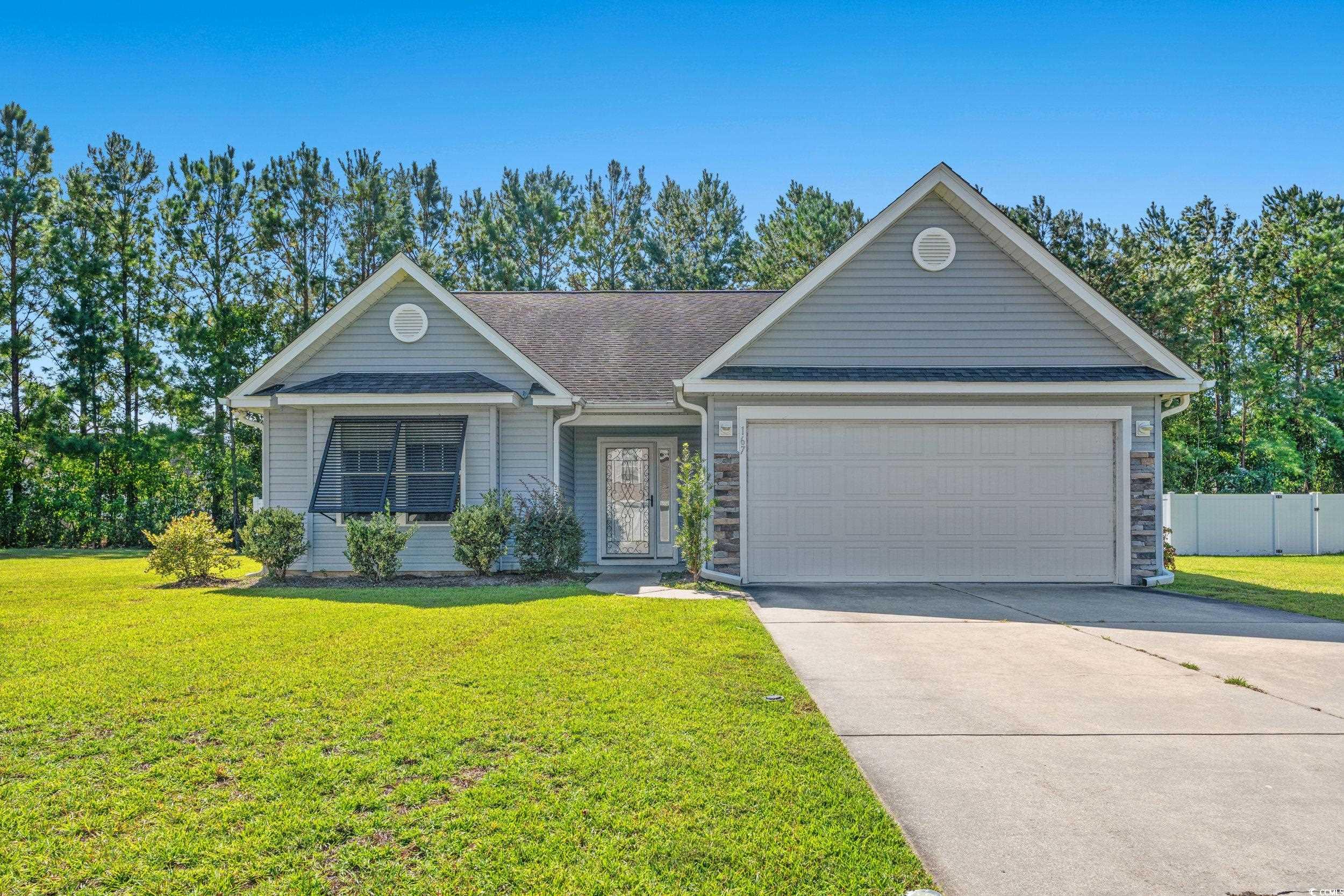 Ranch-style home featuring a front yard and a gara