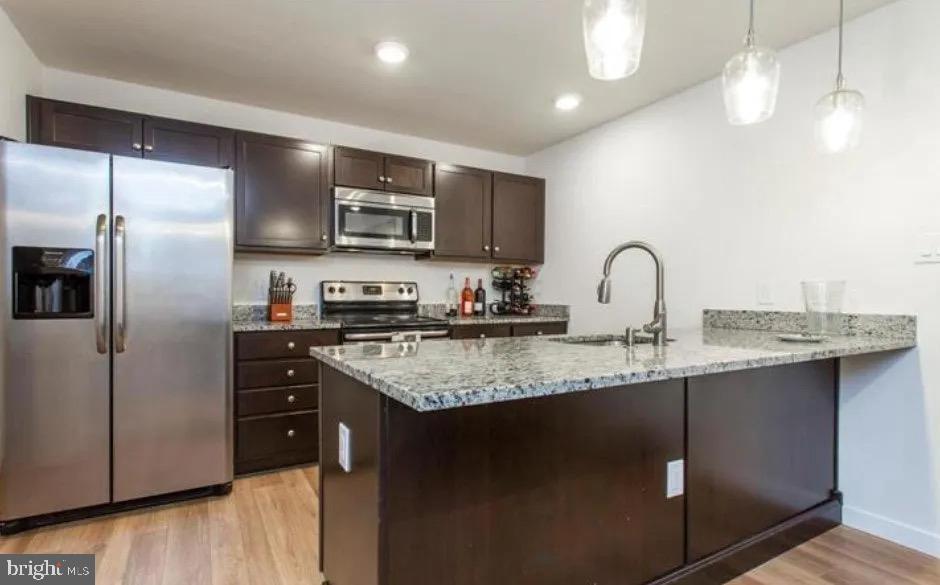 a kitchen with stainless steel appliances granite countertop a sink a stove and refrigerator