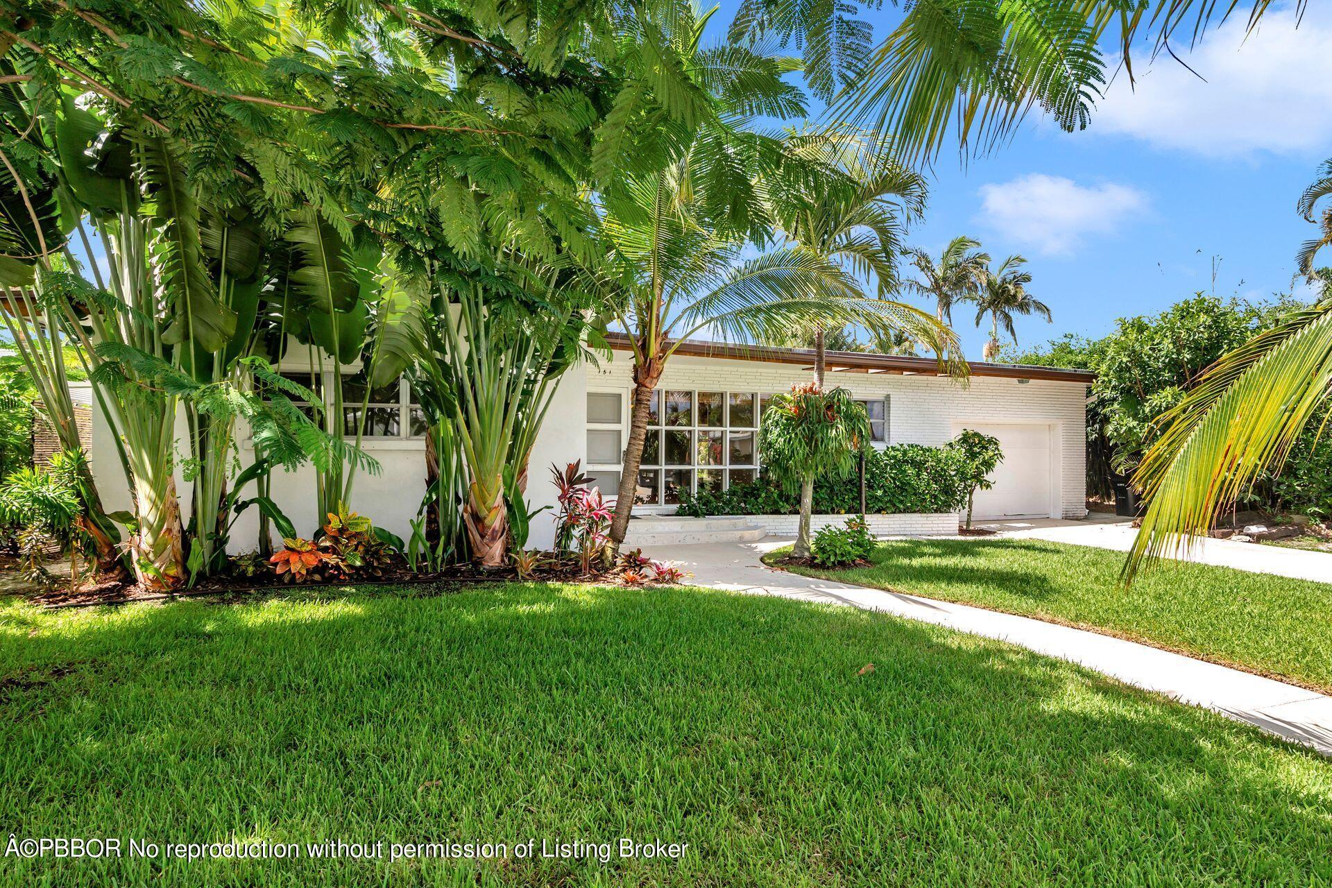 front view of a house with a yard and palm trees