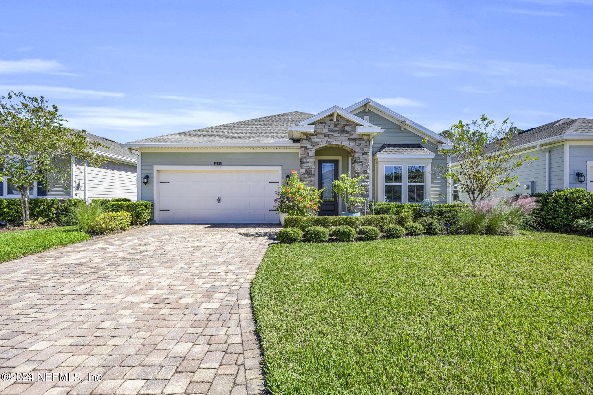 a front view of a house with a yard and potted plants