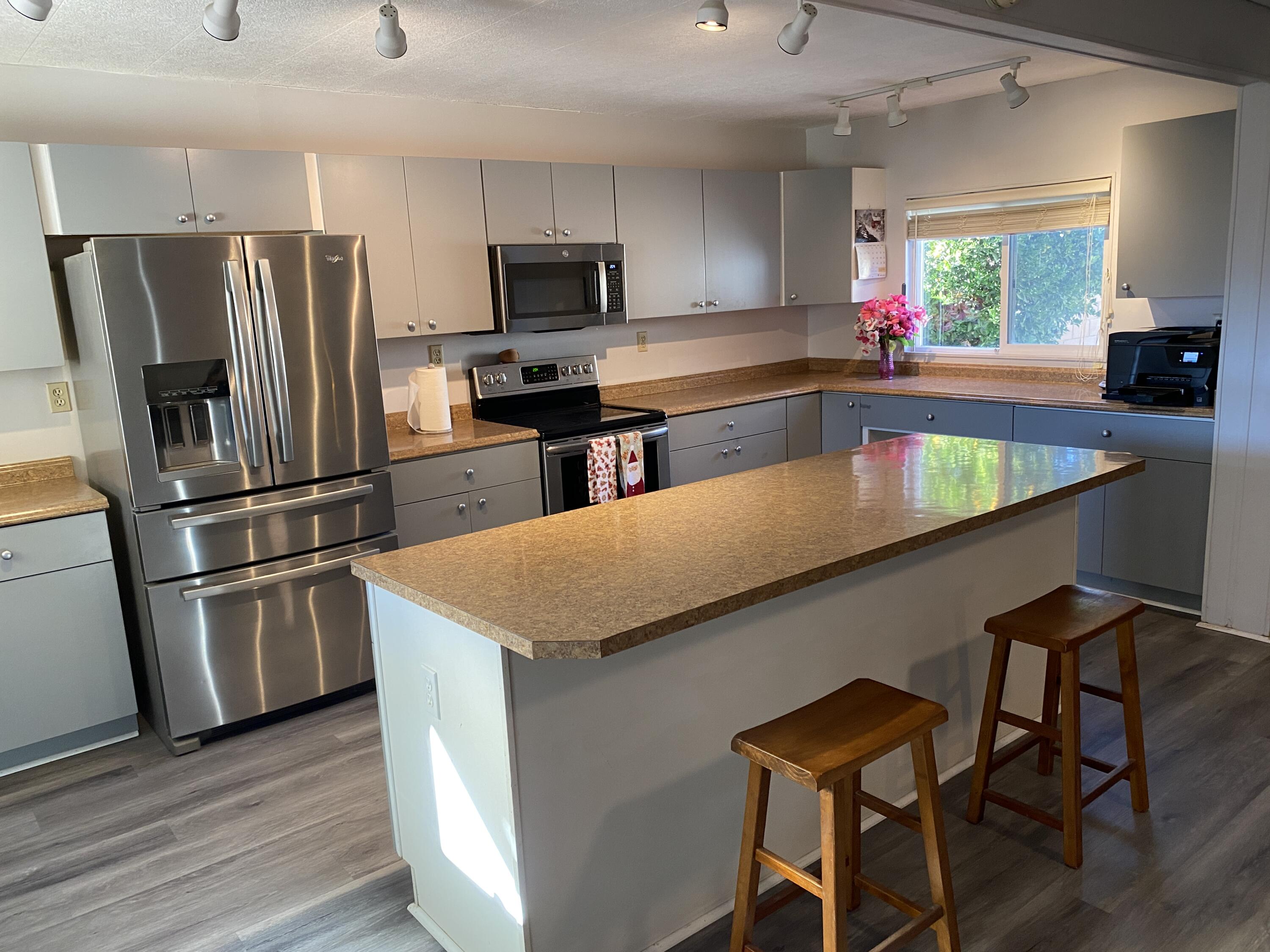 a kitchen with stainless steel appliances granite countertop a refrigerator a stove top oven a sink dishwasher and a refrigerator with wooden floor