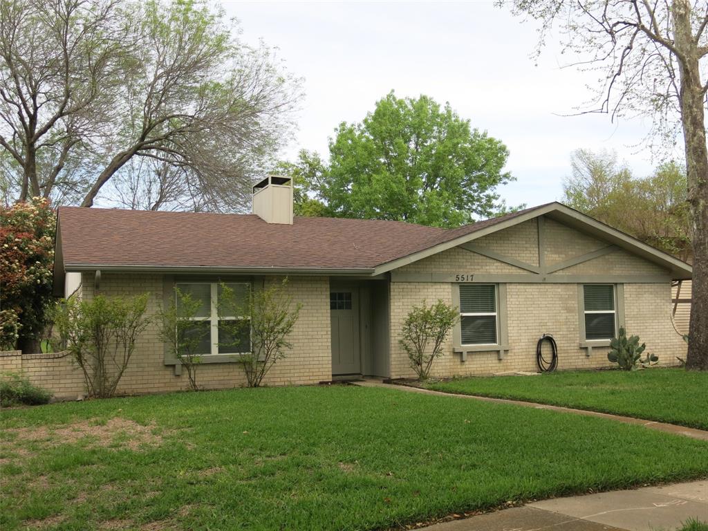 a view of a yard in front of a house with large windows