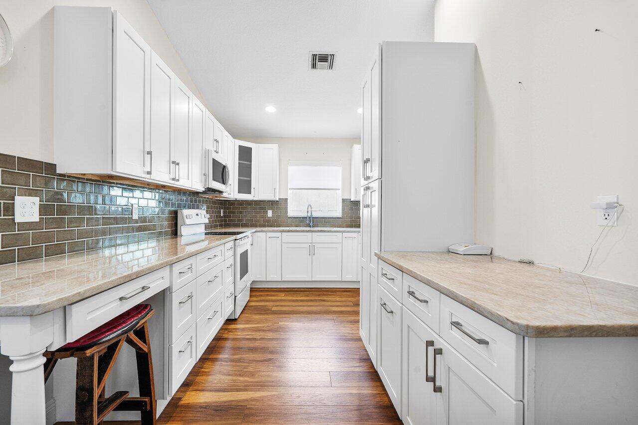 a kitchen with granite countertop white cabinets and white appliances