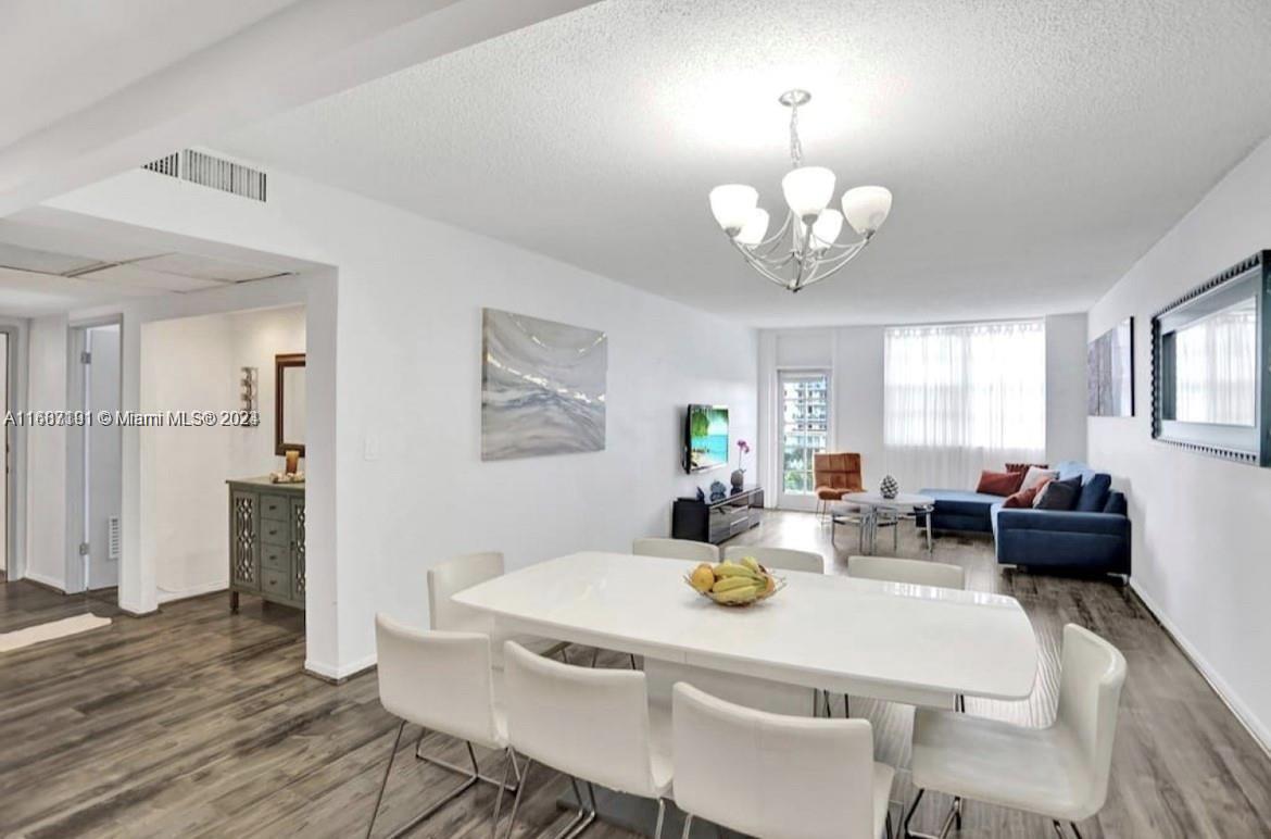 a view of a dining room with furniture a chandelier and wooden floor