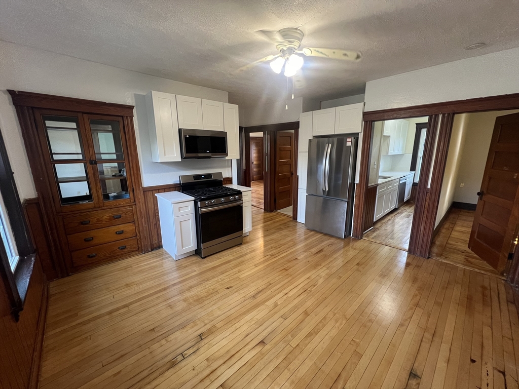 a view of a livingroom with wooden floor and a ceiling fan