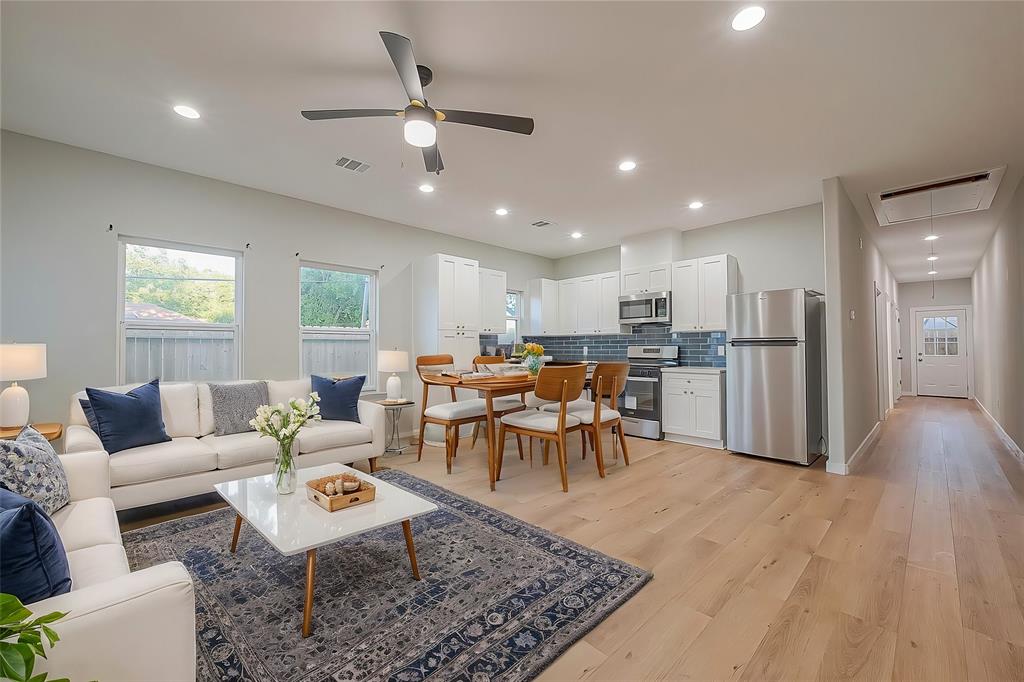 a living room with lots of furniture and kitchen view with wooden floor