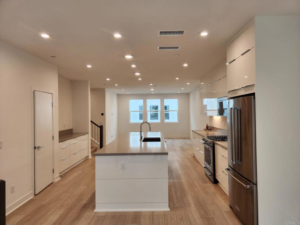 a living room with stainless steel appliances furniture refrigerator and wooden floor