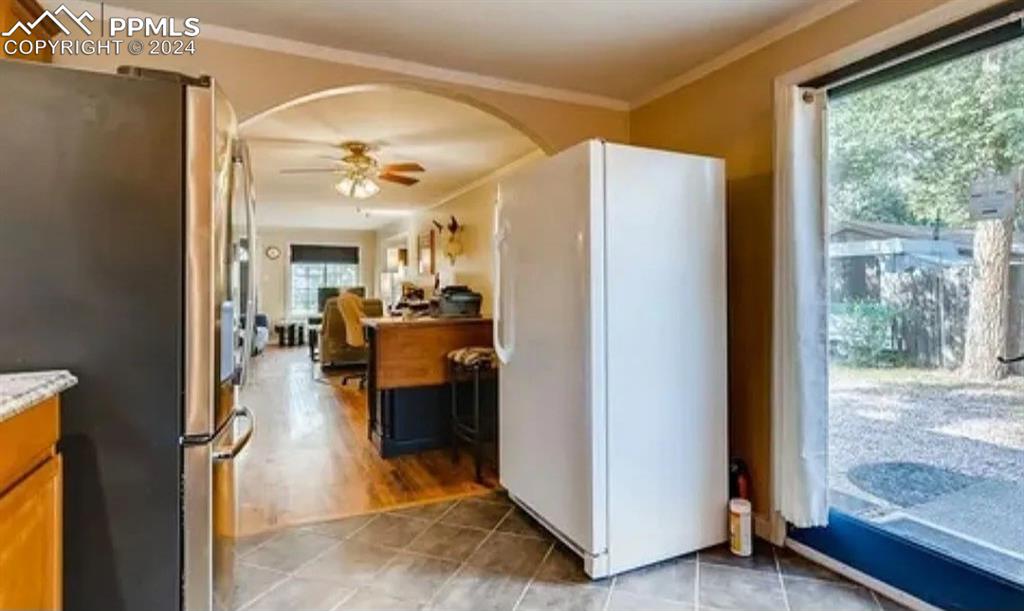 Kitchen with stainless steel refrigerator, ceiling fan, white fridge, and a healthy amount of sunlight