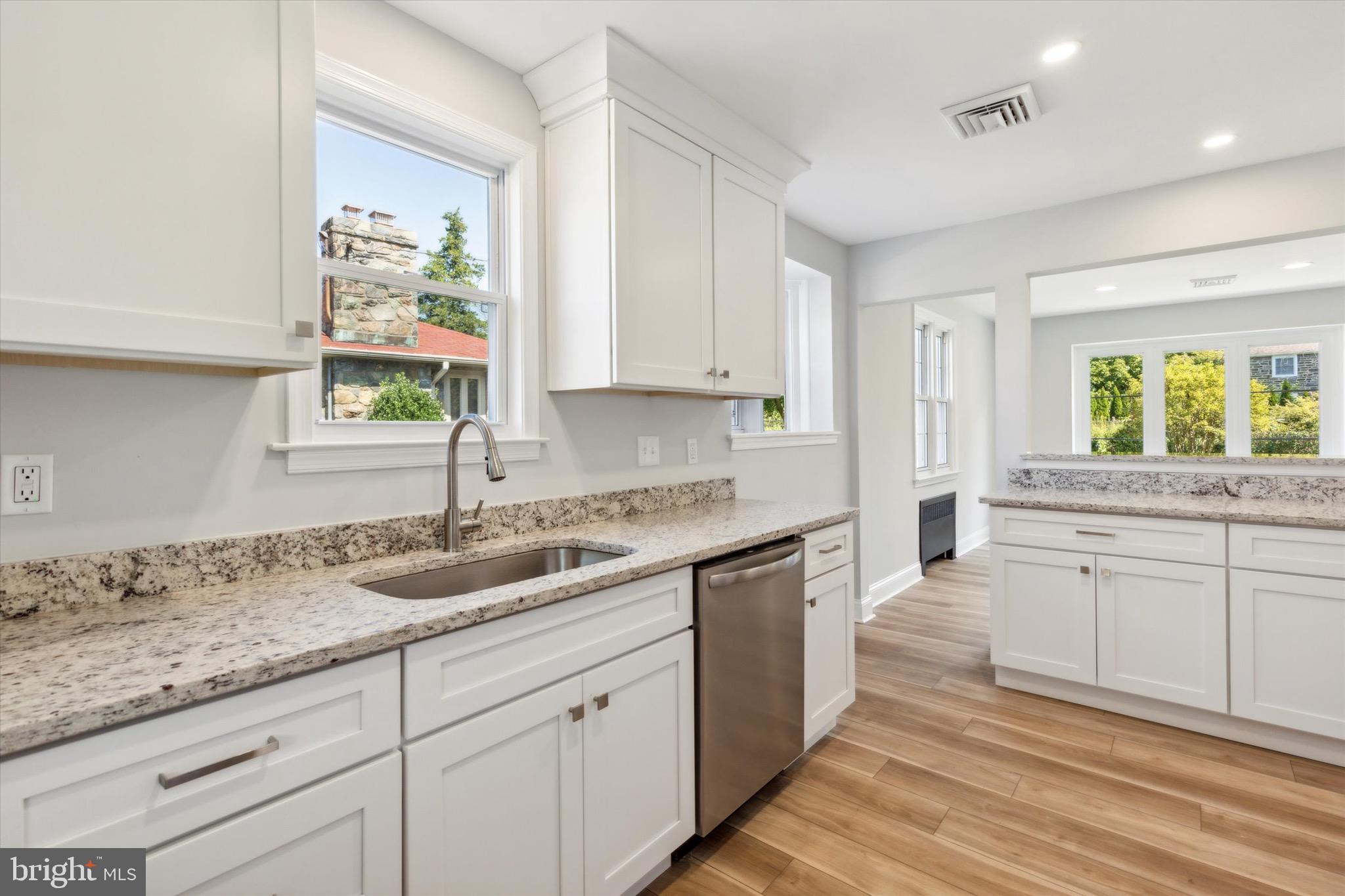 a kitchen with granite countertop white cabinets and a window