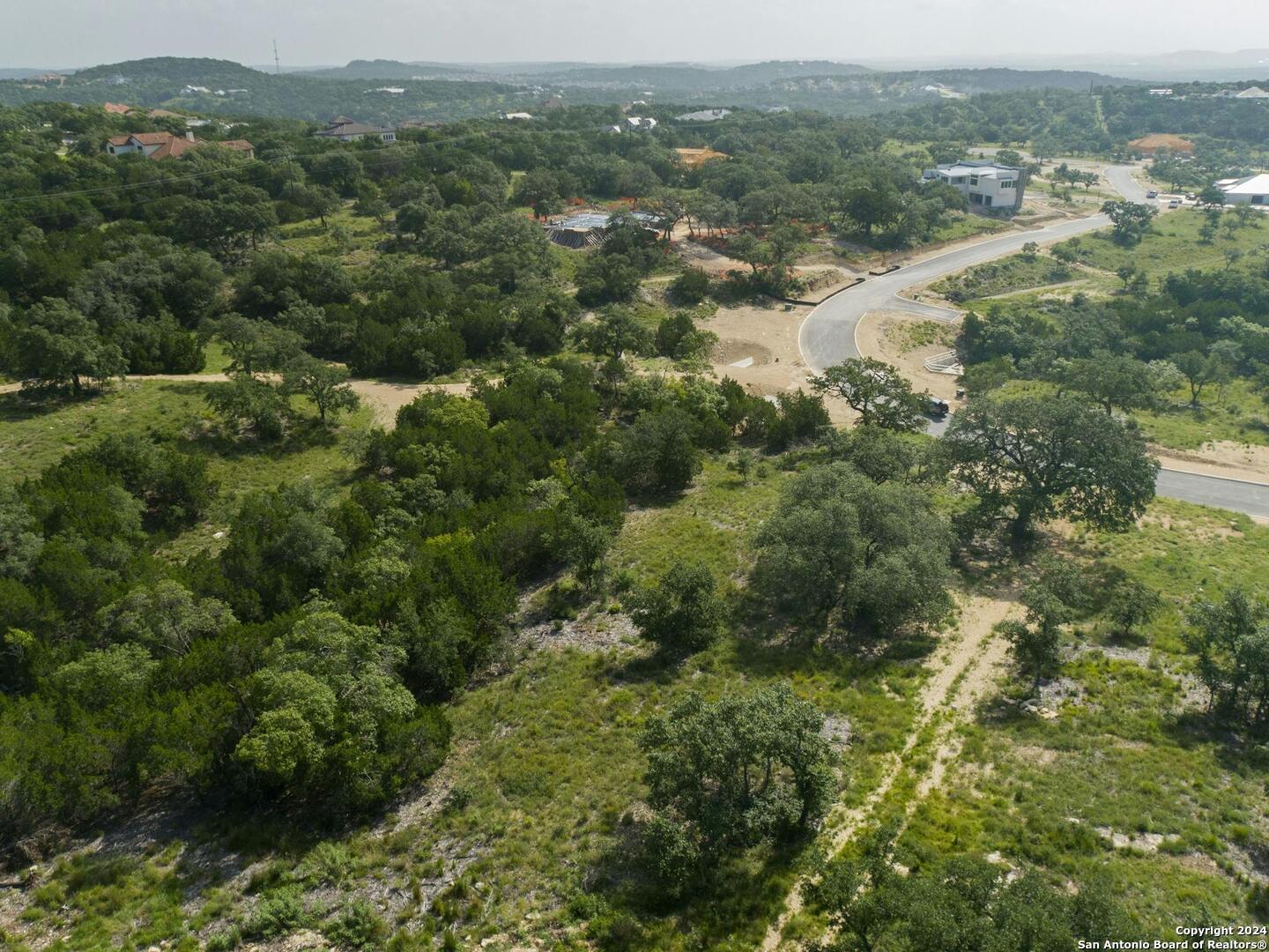 an aerial view of residential houses with outdoor space and trees