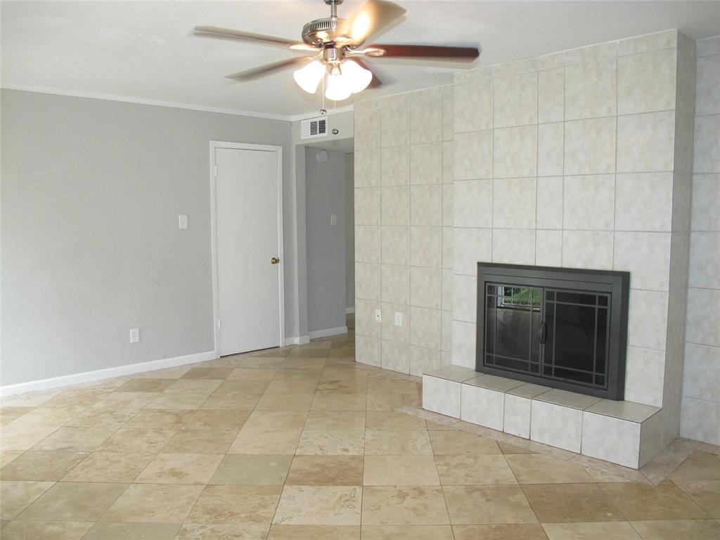 an empty room with a fireplace and a ceiling fan