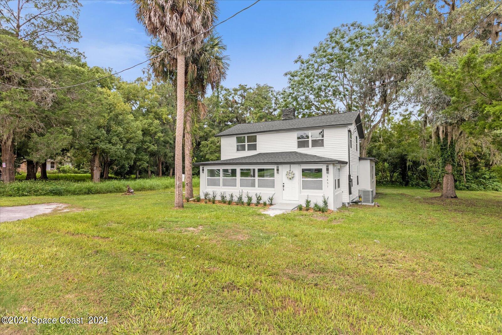 a view of a house with a big yard and large trees