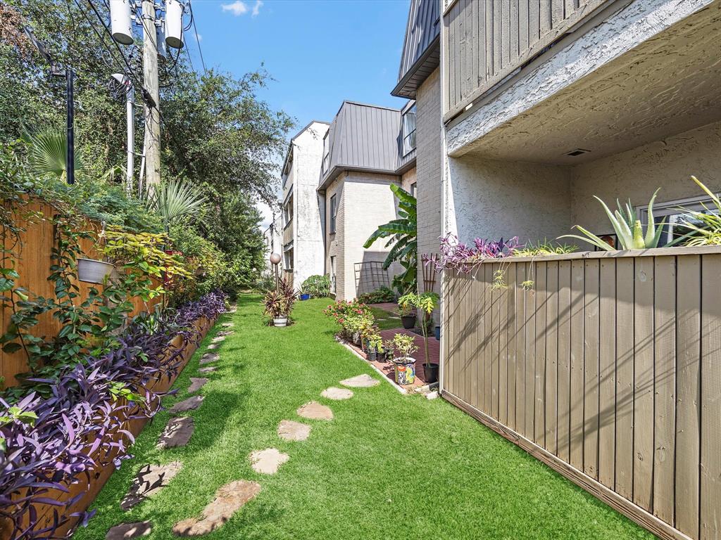 Lushly landscaped backyard with vibrant plants, stone pathway, and privacy fence.