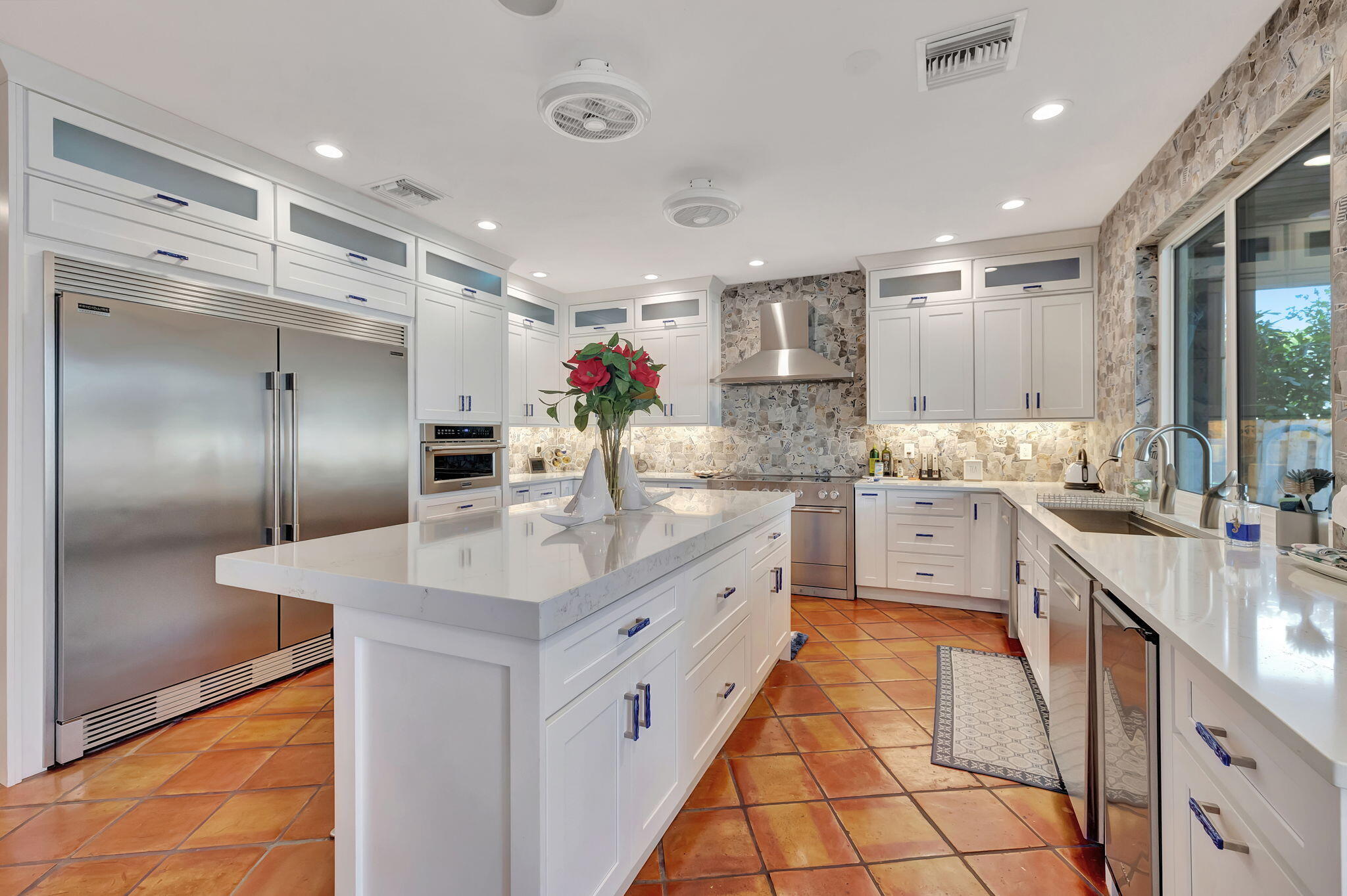 a large white kitchen with kitchen island a sink appliances and cabinets