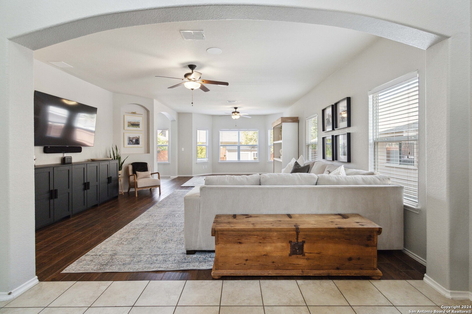 a living room with couches and flat screen tv with kitchen view