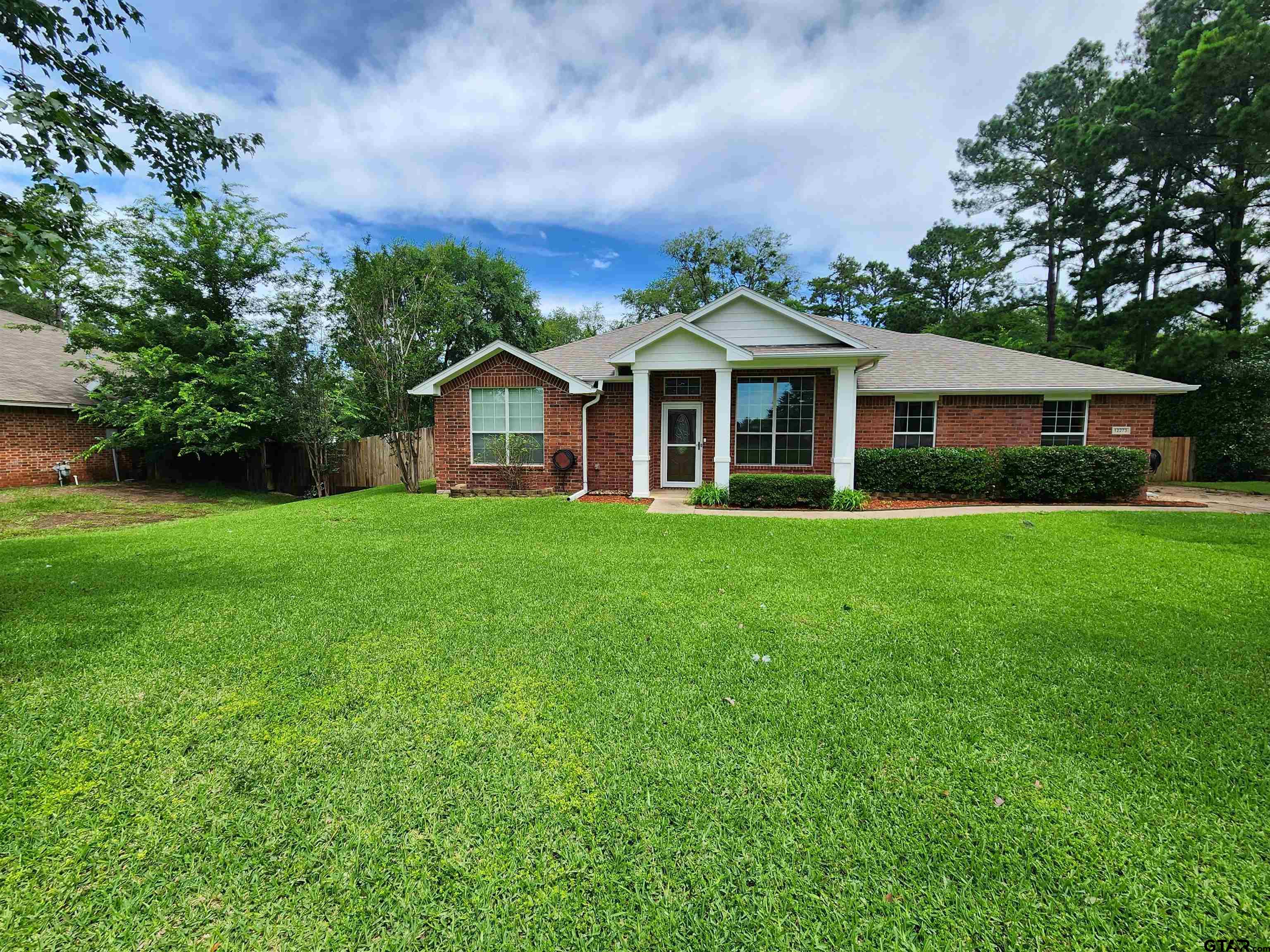 a view of a house with a big yard and large trees